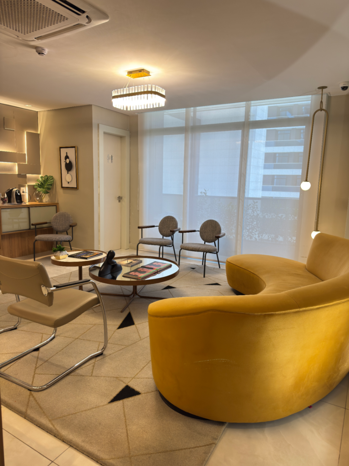 Sala de espera da clínica com sofá amarelo e iluminação acolhedora